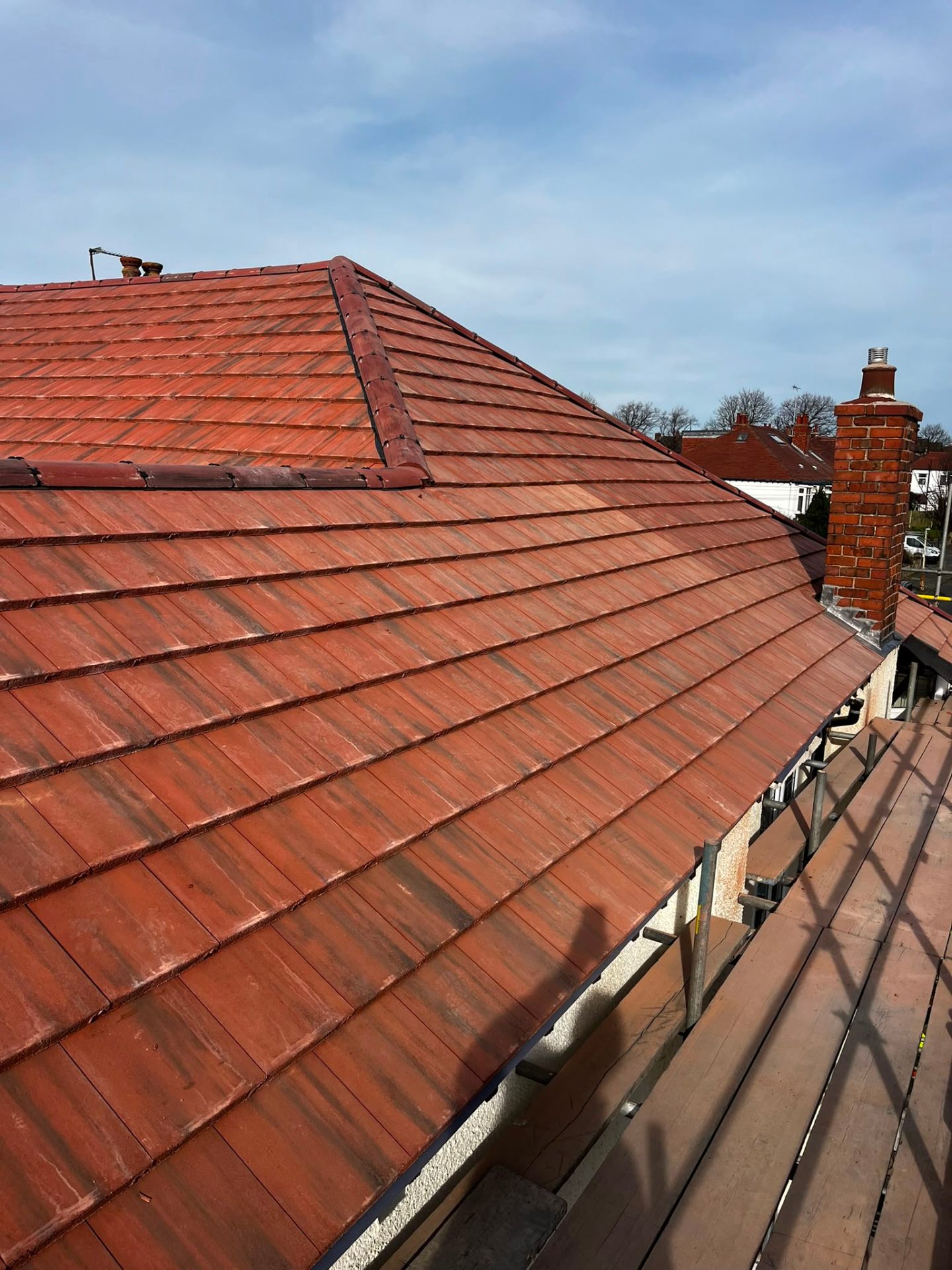 Roofer mid-installation dressing dry-ridge on a grey concrete pantile re-roof by RTC Roofing