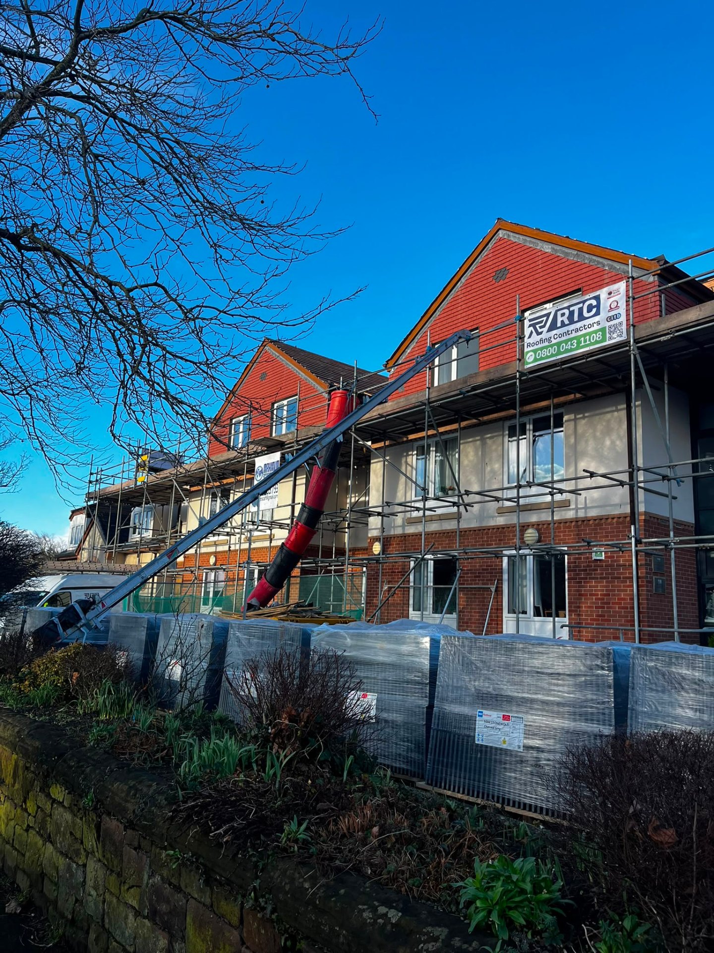 RTC Roofing site banner on scaffold at a large gabled property mid re-roof, Wirral